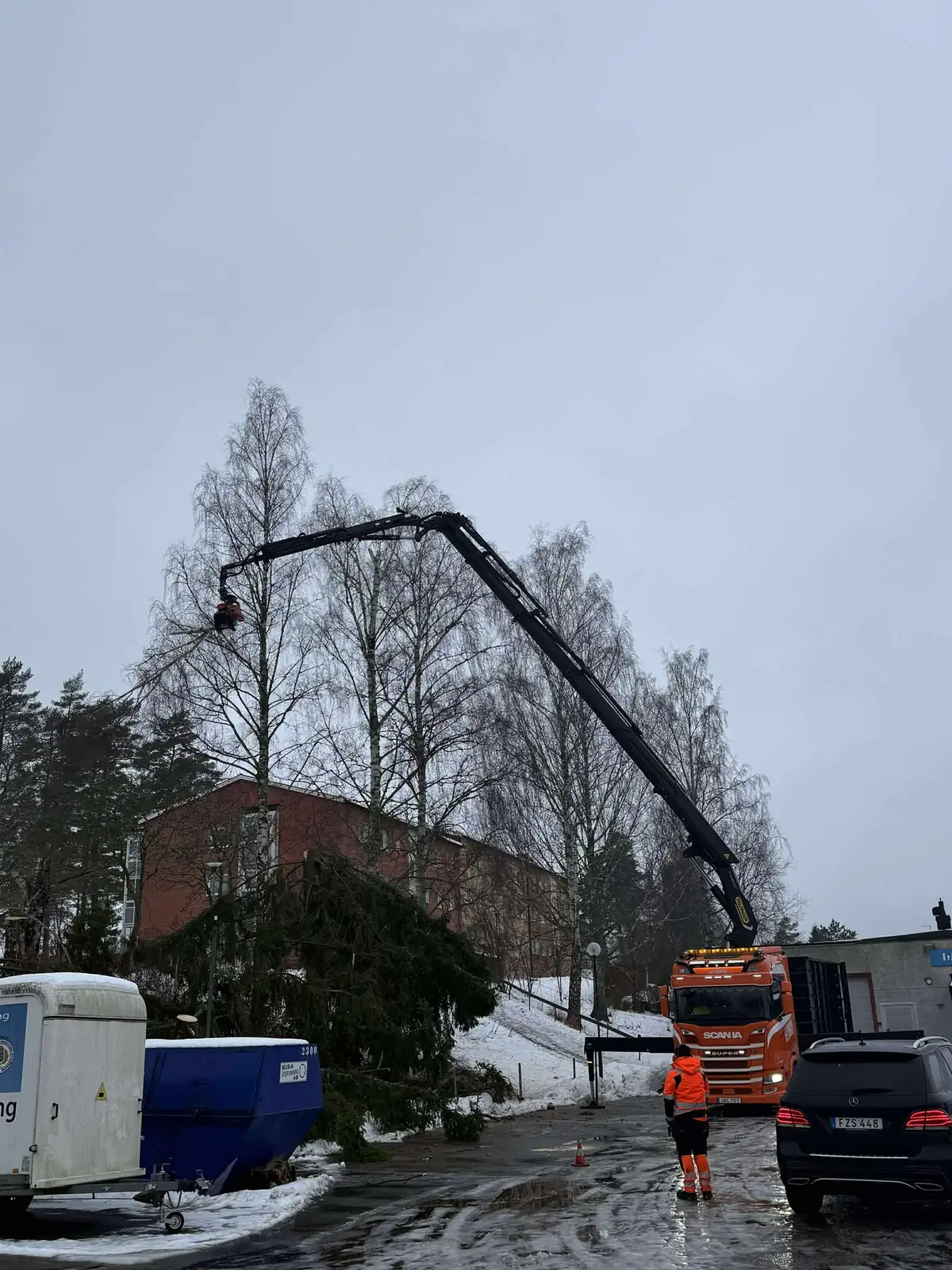 Trädplockning med kransåg i Kisa - Lywén kranbil med lång kranarm plockar ner träd säkert i bostadsområde